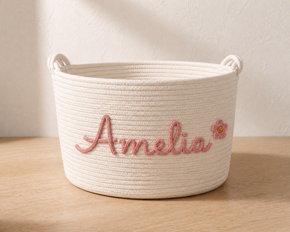 A white woven basket with the name "Amelia" embroidered on it in pink.