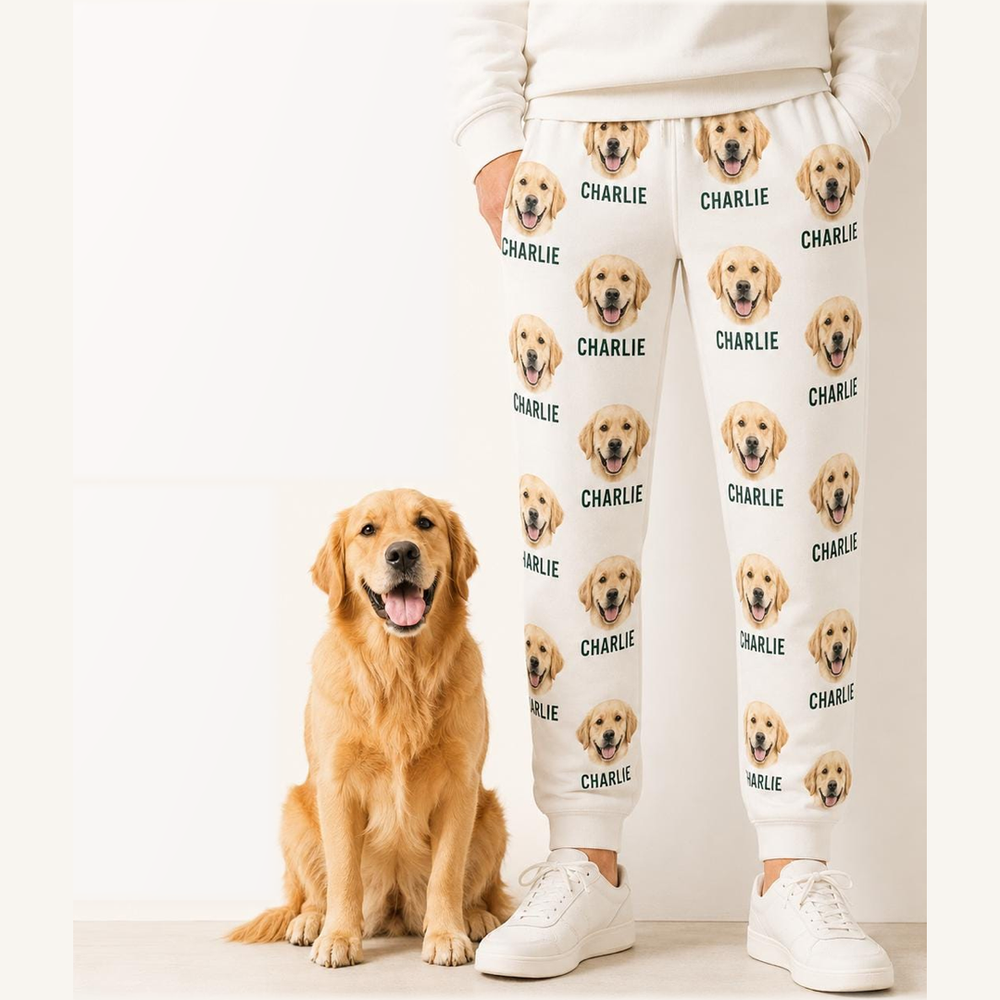 Personalized white pet-face sweatpants with repeating golden retriever portrait and Charlie name print, shown full length beside the matching dog.